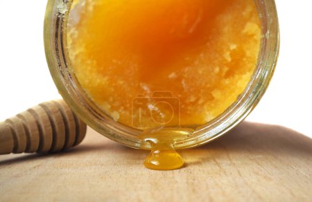 Photo for Drop leaking from a jar of crystallized honey. Melted honey. Focused on honey drop. - Royalty Free Image