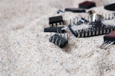 Téléchargez les photos : Éléments électroniques semi-conducteurs sur le sable. Circuits intégrés, transistors. - en image libre de droit
