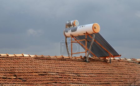 Téléchargez les photos : Chauffe-eau solaire et réservoir sur le toit d'une maison. Obtenir de l'eau chaude avec l'énergie solaire. Systèmes solaires d'eau chaude domestique. - en image libre de droit