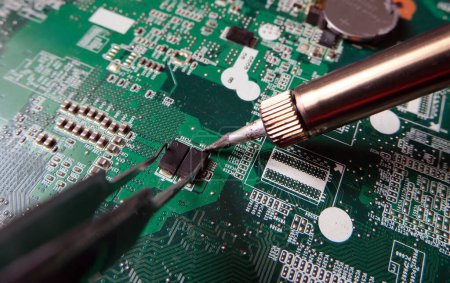 Foto de Montaje o desmontaje de componentes en placas de circuitos electrónicos de alta tecnología. Trabajar con semiconductores. - Imagen libre de derechos