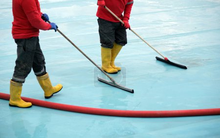 Workers cleaning floors with squeegees