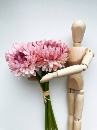 Téléchargez les photos : Marionnette en bois avec un bouquet de fleurs. Photo de haute qualité - en image libre de droit