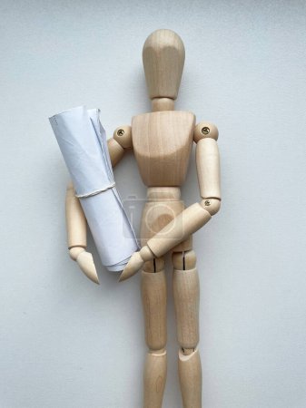 Photo for A wooden mannequin holds a roll of drawing paper . High quality photo - Royalty Free Image