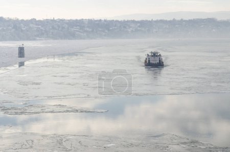 Donau mit Schnee und Eis bedeckt. Ein Eisbrecher in der gefrorenen und schneebedeckten Wasserstraße der Donau unterhalb der Festung Petrovaradin, Vojvodina, Novi Sad, Petrovaradin, Serbien.
