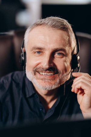 Photo for Middle-aged call center agent looking at camera with smile. Front view of happy telemarketer operator wearing headset. Hotline manager talking to client. High quality photo - Royalty Free Image