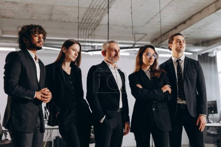 Foto de Ambitious business team posing together. Group of confident businesspeople in suits standing in office. High quality photo - Imagen libre de derechos