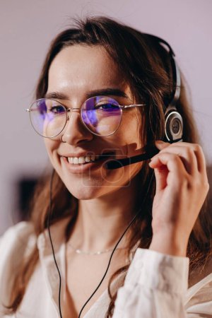 Foto de Retrato del trabajador del centro de llamadas. Chica sonriente con gafas trabajando como agente de apoyo. Vista de cerca de la mujer de negocios en auriculares. Foto de alta calidad - Imagen libre de derechos