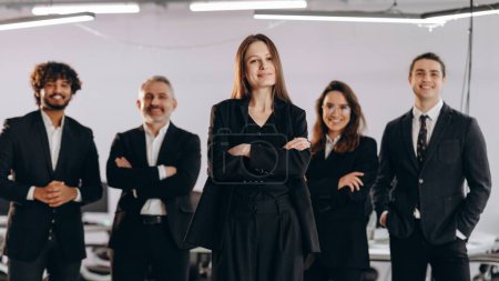 Foto de Company executive woman posing with her employees. Female team leader and her coworkers standing in confident pose. High quality photo - Imagen libre de derechos