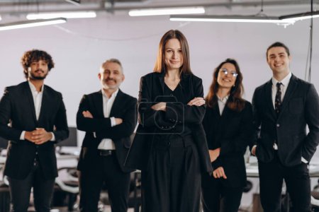 Photo for Female boss and her business team. Empowered woman posing with coworkers in office. Female company head standing with arms crossed near her employees. High quality photo - Royalty Free Image