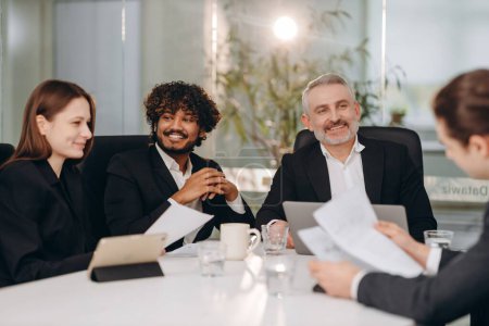 Photo for Diverse businesspeople discussing business project. Business team smiling at conference. Coworkers laughing during brainstorming in meeting room. High quality photo - Royalty Free Image