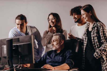 Photo for A team of IT specialists are examining something on a monitor screen. A senior employee of an IT company shows his work to his colleagues. High quality photo - Royalty Free Image