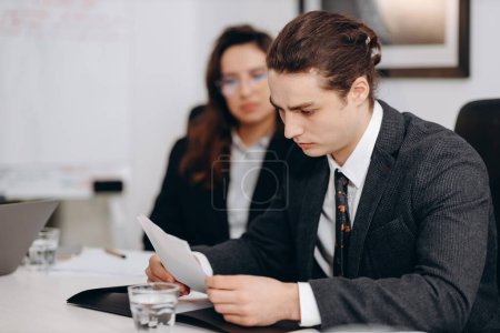Photo for Focused businessman reading document. Young manager in formal wear doing paperwork. Serious office worker at the business meeting. High quality photo - Royalty Free Image