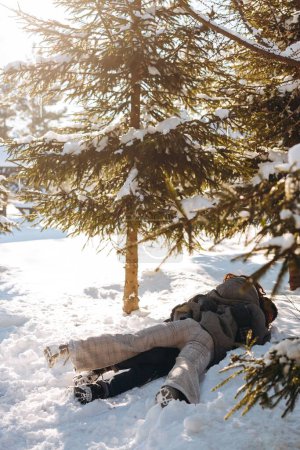 Photo for A man hugs his girlfriend lying on the snow. A young couple have fun on their day off walking through a snowy sunny forest. High quality photo - Royalty Free Image