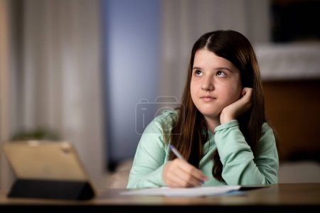 Foto de Estudiante de primaria que estudia en línea. Colegiala utilizando la tabla digital para las lecciones en línea. Foto de alta calidad - Imagen libre de derechos