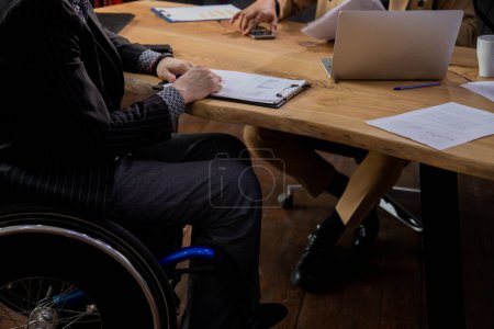 Photo for Cropped view of a man in a wheelchair sitting at a table. Two men in formal suits are having a business conversation. High quality photo - Royalty Free Image
