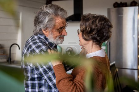 Téléchargez les photos : Les couples âgés dansent dans la cuisine et se regardent avec amour le jour de leur anniversaire. Photo de haute qualité - en image libre de droit