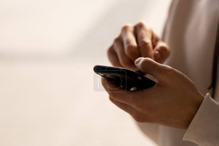 Photo for Cropped view of man tapping smartphone screen. A man in a white sweater is writing something on his smartphone. High quality photo - Royalty Free Image