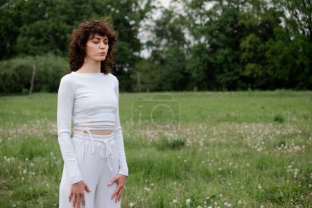 Photo for Sportswoman closed her eyes to focus on breathing fresh air. Woman doing meditation technique for relax mind. Female yoga instructor showing pranayama practice on park background. High quality photo - Royalty Free Image