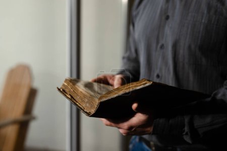Photo for Close up shot bible. Alone male prayer reading old literature. Man in black shirt holding religious holy book. Hope for salvation. Exploration of traditional spiritual scripture. High quality photo - Royalty Free Image
