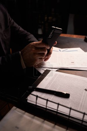 Photo for Businessman photographing license agreement documents. Business man holding smartphone to shooting confidential information. Male entrepreneur browsing social media at late night paperwork. High - Royalty Free Image