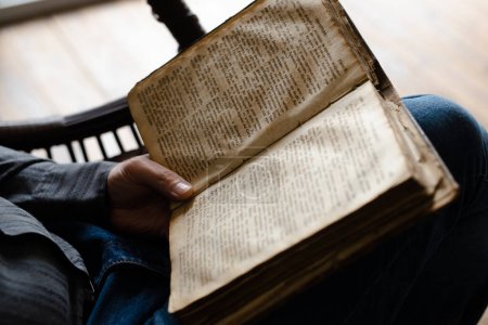 Photo for Close up shot of reading lines from the Bible. Man hands holding a big heavy book. Male studying christianity rules and duties. Relaxation when he learning ancient literature. High quality photo - Royalty Free Image