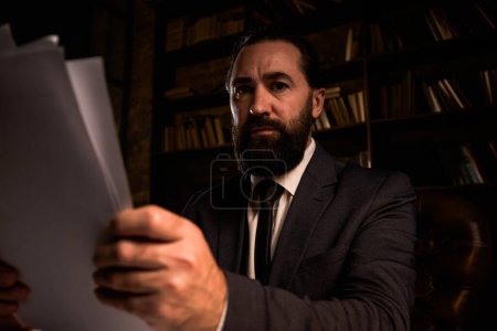 Photo for Focused businessman sit at private office doing finance accountant. Ponder bearded male holding documents with confidential information. Business man preparing contract to sign. High quality photo - Royalty Free Image