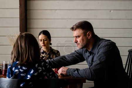 Photo for Concept of family hard talk on dining table. Stressed father with sad mother dissatisfied their kid bad marks. Problems in school. Two parents dislike child education progress. High quality photo - Royalty Free Image