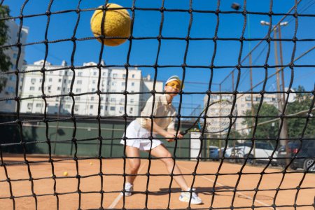 Photo for Young girl playing tennis at the court. Female tennis player hitting the ball. Sports woman reaching to hit the tennis ball on court. Game in action. Sportive lady with racket. High quality photo - Royalty Free Image