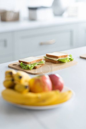 Photo for Ready sandwiches with cabbage and cheese lie on a wooden board in the kitchen. The plate with apples and bananas in the foreground. Blur effect. Close up. The selective focus mode. High quality photo - Royalty Free Image