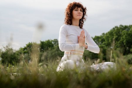 Photo for Girl testing new technique for breathe clearly. Sports woman spend time outdoor alone in nature. Female doing yoga exercise to open her chakra. Hands together sit lotus position. High quality photo - Royalty Free Image