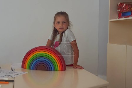 Téléchargez les photos : Girl playing with colorful wooden toy rainbow in the children room. Non plastic wooden toys concept. Defocused image - en image libre de droit