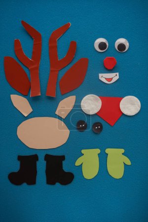 Foto de Christmas New Year Santa's deer handmade. Step by step photo instruction. DIY concept. Step 2-13. Preparation elements. Cut, draw - eyes, nose, antlers, mittens, boots, scarf. Top view, Flat lay - Imagen libre de derechos
