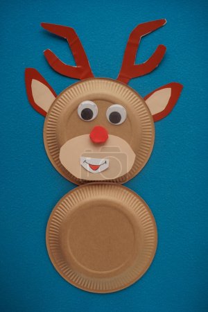 Foto de Christmas New Year Santa's deer handmade. Step by step photo instruction. DIY concept. Step 9-13. Cut out a red round cute nose and glue it to the face of the deer. Top view, Flat lay - Imagen libre de derechos