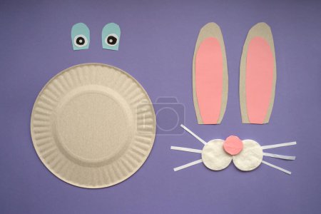 Foto de How to make paper bunny for Easter greetings. Children art project. Step by step photo instruction. DIY concept. Very Peri background color. Flat lay. Step 3 Assemble the parts, use a glue stick. - Imagen libre de derechos