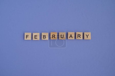Photo for The name of the month FEBRUARY is written on wooden cubes isolated. Very Peri Color of the Year background, copy space. Top view of wooden blocks with letters. Step by step, step 2. - Royalty Free Image