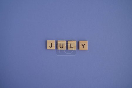 Photo for The name of the month of July is written on wooden cubes isolated. Very Peri Color of the Year background, copy space. Top view of wooden blocks with letters. Step by step, step 7. - Royalty Free Image