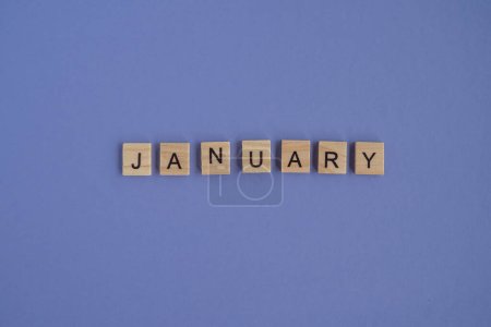 Foto de The first month of the year JANUARY -from isolated letters on wooden blocks in natural color, in high resolution. Very Peri background, copy space. Flat lay, step by step, step1 - Imagen libre de derechos