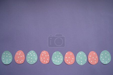 Foto de Easter card with vertically arranged paper eggs. option 1 Decorated paper Easter eggs and copy space for text on a colored background, top view. Very Peri background color. - Imagen libre de derechos