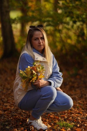 Photo for Sad woman sitting in the park resting feeling nostalgic. Unhappy melancholic person sitting on the ground in autumn season. - Royalty Free Image