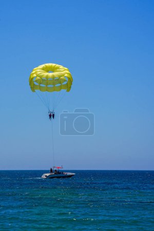 Photo for Parasailing on a yellow parachute against the blue sky. Beach extreme adventures. Background vacation, photo for postcards, tourist and travel guide. The concept of summer holidays, vacation, tourism. - Royalty Free Image