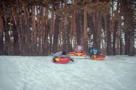 Photo for Children and parents have fun riding from the snowy mountain on tubing. Group of children sliding down on tubes - Royalty Free Image