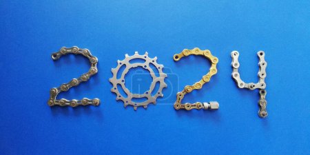 2024 Ciclos concepto fondo con cadena de oro y parte de bicicleta sobre fondo azul