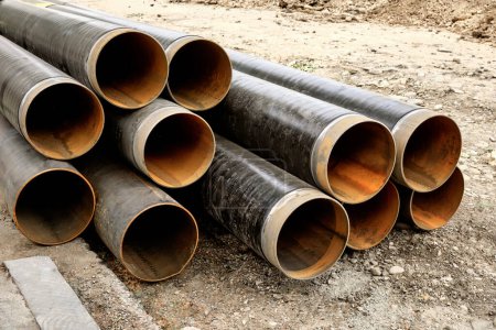 Foto de Primer plano de una gran cantidad de tuberías de hierro para el suministro de agua. Reconstrucción del gasoducto y alcantarillado en la ciudad. - Imagen libre de derechos