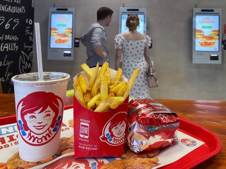 Photo for Close-up of french fries, drink and burger on a tray at Wendys fast food restaurant. Against the backdrop of visitors choosing their own meals in the terminal: Batumi, Georgia, July 14, 2023. - Royalty Free Image