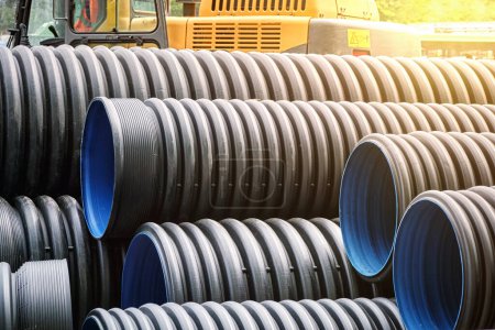 Photo for Close-up of large plastic corrugated pipes for water supply against the background of construction equipment. Reconstruction of the pipeline and sewerage in the city. - Royalty Free Image