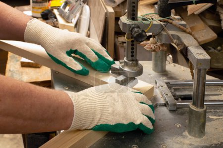 Ein Schreiner arbeitet in seiner Werkstatt. Nahaufnahme der Verarbeitung von Holzplatten auf einer Brettleimmaschine.