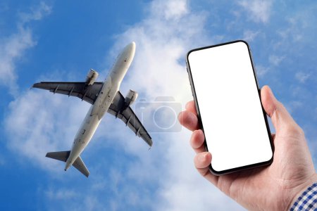 Ein Mann hält ein Smartphone in der Hand. Vorlage für Design. Ein großes Passagierflugzeug fliegt gegen einen blauen Himmel mit schönen Wolken. 