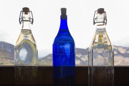 Téléchargez les photos : Three bottles by the window against the backdrop of the mountains - en image libre de droit