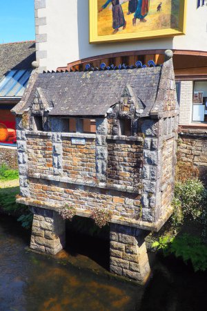 Téléchargez les photos : Pont-Aven, in Brittany, is a city known for all its famous painters. Leaning against the hold of the bridge, a charming little building attracts attention. These are the public toilets built in 1932 - en image libre de droit