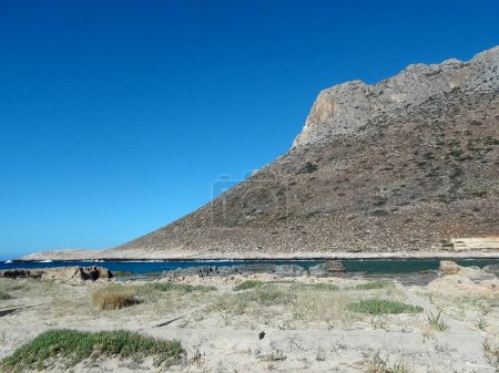 Photo for In Crete (greece), near Chania (or Xania or La Canee), the famous beach of Stavros, and the rock facing it, on which Anthony Quinn danced the sirtaki, to the most famous music by mikis theodorakis in the film Zorba the Greek - Royalty Free Image